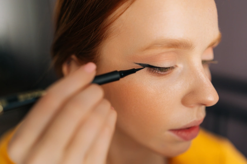 Kobieta malująca kreskę eyelinerem